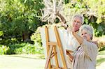 Man and a woman painting on a canvas in a park