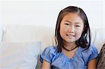 A portrait shot of a smiling girl as she sits on the couch.