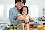 Un père et une fille souriante dans la cuisine afin de préparer le dîner de concombres de coupe