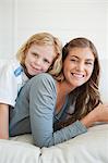 A close up shot of a son lying on his mother as they both smile on the couch