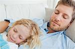 Un plan d'un garçon et son père endormi sur le canapé, car ils ont tous deux sourient doucement rapproché