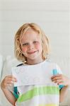 A smiling young boy holds his letter to santa close to his chest