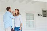 A couple drink from glasses as they cross each others arms while on the porch