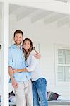 A smiling man and woman looking up from the porch outside