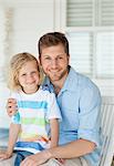 A smiling father and son sit on the seat together as the look straight ahead