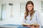 A woman smiling while reading a book outside