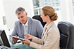 Business people working in a bright office with widows in background