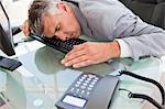 Businessman sleeping on his keyboard in a bright office