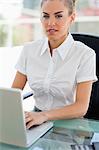 Porträt einer attraktiven krauses kurzhaarige Frau auf einem Laptop in einem hellen Büro arbeiten