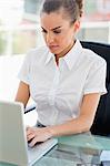 Jolie femme aux cheveux crépuse travaillant avec un ordinateur portable dans un bureau lumineux