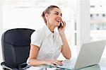 Tanned businesswoman laughing while phoning in a bright office