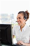 Smiling tanned businesswoman wearing a headset in a bright office