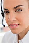 Close-up of a tanned woman wearing headphone in a bright office