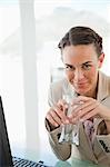 Portrait of a businesswoman holding a glass of water in a bright office