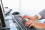 Close-up of a businessman typing on his keyboard in a bright office