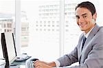 Close-up of a smiling Businessman Tippen auf seiner Tastatur in einem hellen Büro
