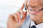 Close-up of a smiling man's mouth talking with a headset in a bright office