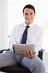 Portrait of a businessman using a touchpad while sitting in a bright office