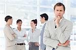 Thoughtful young salesman with his colleagues behind him