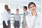 Thoughtful young saleswoman with colleagues behind her