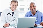 Smiling doctors together with laptop