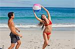 Attraktive Frau spielen mit einem Ball vor ihrem Freund auf der beauch