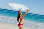 Portrait of a happy woman playing with a sarong with the sea in background