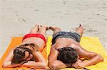 High angle-shot of a tanned couple sleeping on the beach