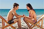 Couple face to face in folding chair with the sea in background