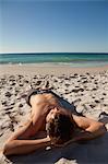 Attraktive junge Mann am Strand direkt am Meer liegen