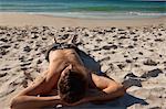 Homme séduisant, allongé sur une plage de sable en face de la mer
