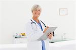 Smiling mature doctor with clipboard and pen