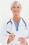 Smiling mature doctor pointing at prescription pad