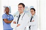 Three smiling doctors with arms crossed standing in front of a window