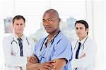 Three doctors with their arms crossed standing in front of a window