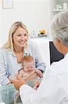 Smiling woman with her little baby seeing the doctor