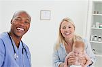 Smiling pediatrician next to woman with her little baby