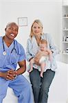 Arzt mit ihr kleines Baby neben Frau sitzt lächelnd