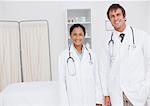 Young smiling doctors standing side by side in a hospital room