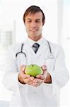 Delicious green apple is in the hands of a smiling surgeon standing in front of a window