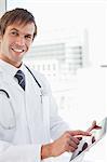 Smiling surgeon using his tablet computer in front of a bright window