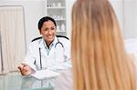 Smiling doctor giving explanations to her patient while sitting at a desk