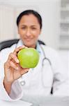 Beautiful green apple being held by a nurse sitting in a medical office