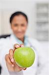 Big green apple being held by a doctor sitting at her desk