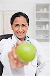 Smiling practitioner holding a delicious green apple