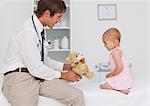 Smiling practitioner offering a teddy bear to a little baby after a consultation