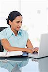 Serious secretary working on her laptop while sitting at a desk