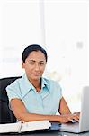 Calm young secretary working with her laptop while sitting at a desk