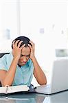 Upset secretary placing her hands on her head while sitting at a desk