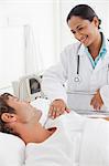 Smiling doctor speaking with her patient lying in a hospital bed